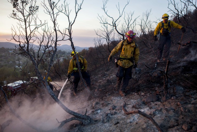 Image: Fire crew put out smouldering embers from the Cocos Fire in San Marcos