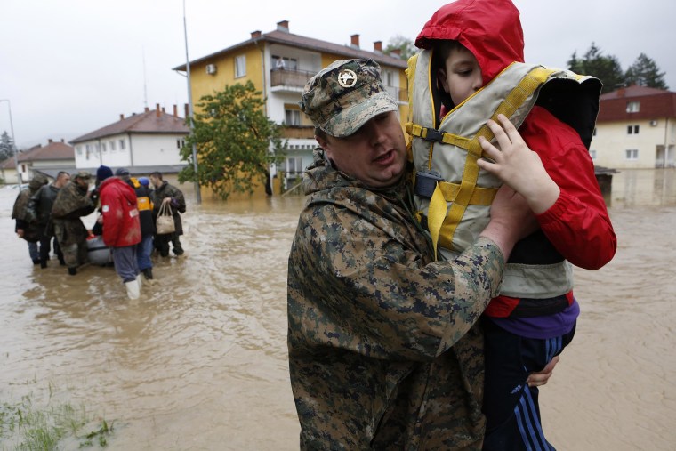 Image: A member of the Bosnian army carries a boy rescued from his home, during floods, in the Bosnian town of Maglaj