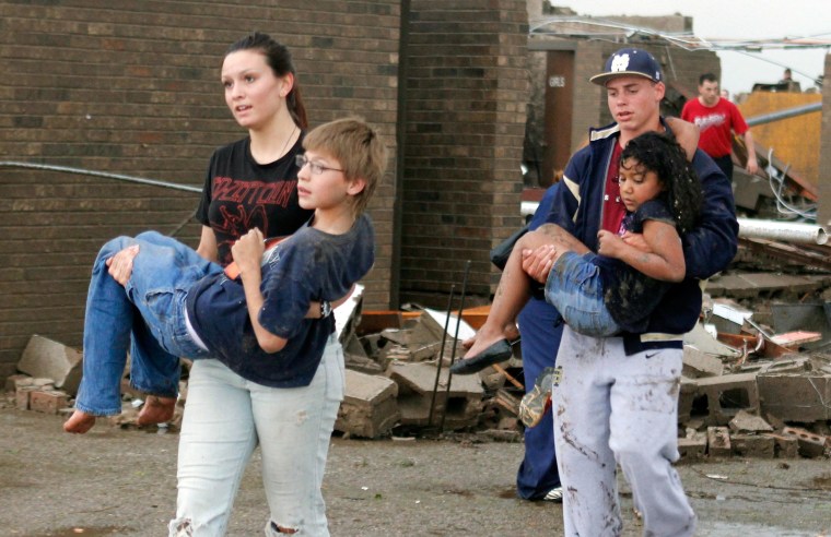 Image: Teachers carry children away from Briarwood Elementary school after a tornado 