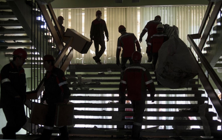 Image: Workers of the Ukrainian company Metinvest clear away debris in a government building in the eastern Ukrainian city of Mariupol, on Frida