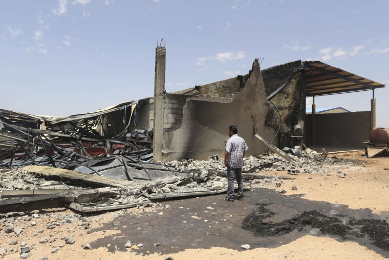 Image: A man looks at destroyed warehouses following Friday's clashes between Libyan irregular forces and Islamist militias in Benghazi