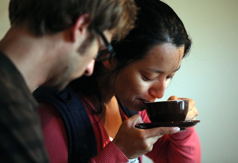 Image: A woman sips a cup of coffee.