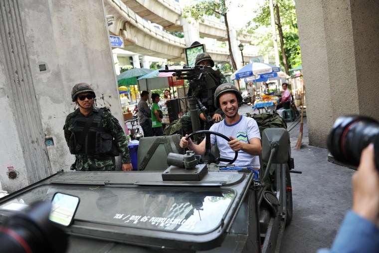 Image: A foreign tourist poses for a photo as Thai army soldiers stand guard on a city center street after martial law was declared on Thailand