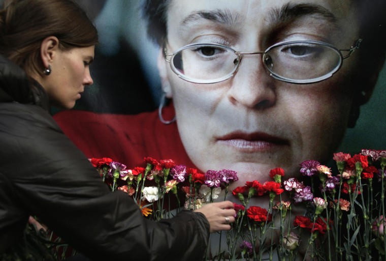 Image: A woman places flowers before a portrait of slain Russian journalist Anna Politkovskaya