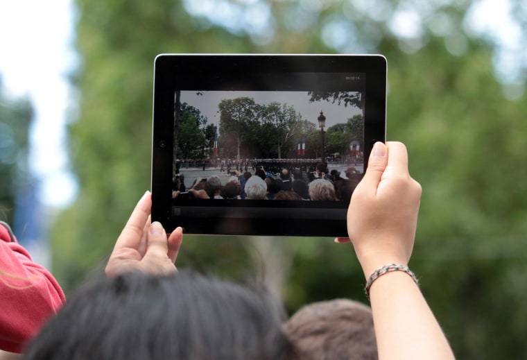 Image: A woman takes a picture with an iPad