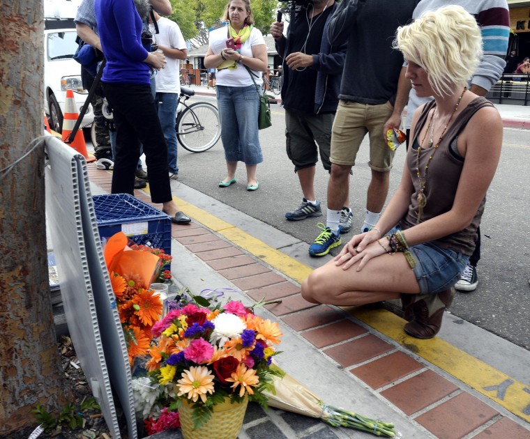 Image: A woman kneels in front of a makeshift memorial for victims of a deadly shooting in Isla Vista.
