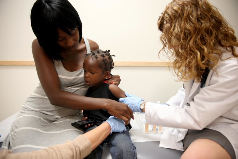 Image: Shakeithia Roberts holds her son, Jermaine Roberts , as pediatrician Amanda Porro M.D. administers a measles vaccination