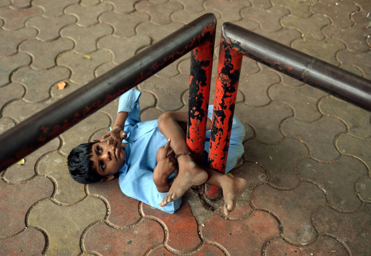 Image: Indian boy Lakhan Kale is tied with a cloth rope around his ankle, to a bus-stop pole in Mumbai.