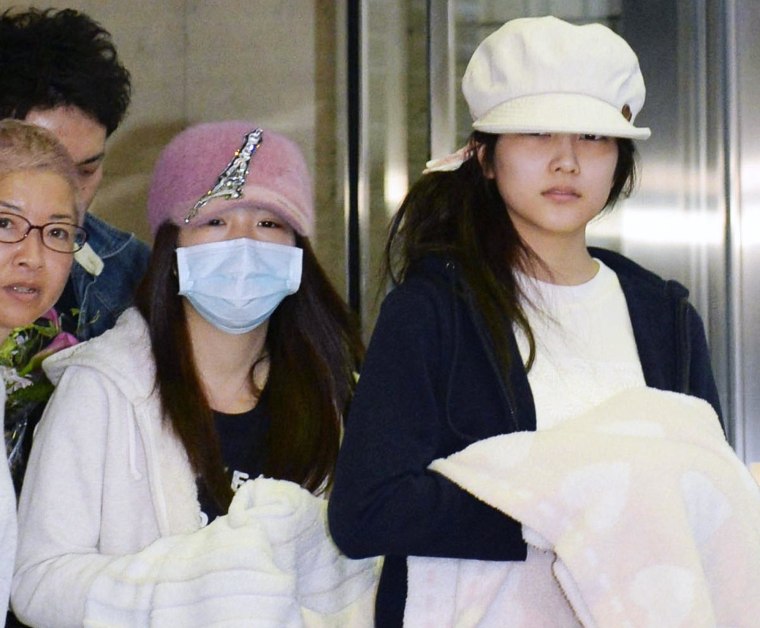 Image: Rina Kawaei, second right, and Anna Iriyama, right, two members of Japan's hugely popular female pop group AKB48, leave a hospital