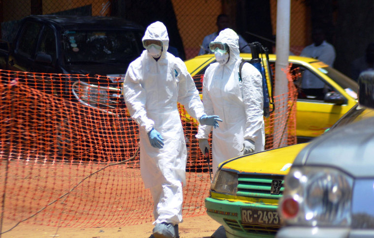 Image: Two members of the Guinean Red Cross, in protective gear, arrive on March 31, 2014 to evacuate the bodies of two people who died from the Ebola virus