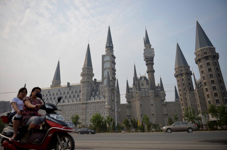 Image: Women ride an electric scooter past buildings, designed based on Gothic architecture, which are part of the Hebei Academy of Fine Arts campus, in Shijiazhuang