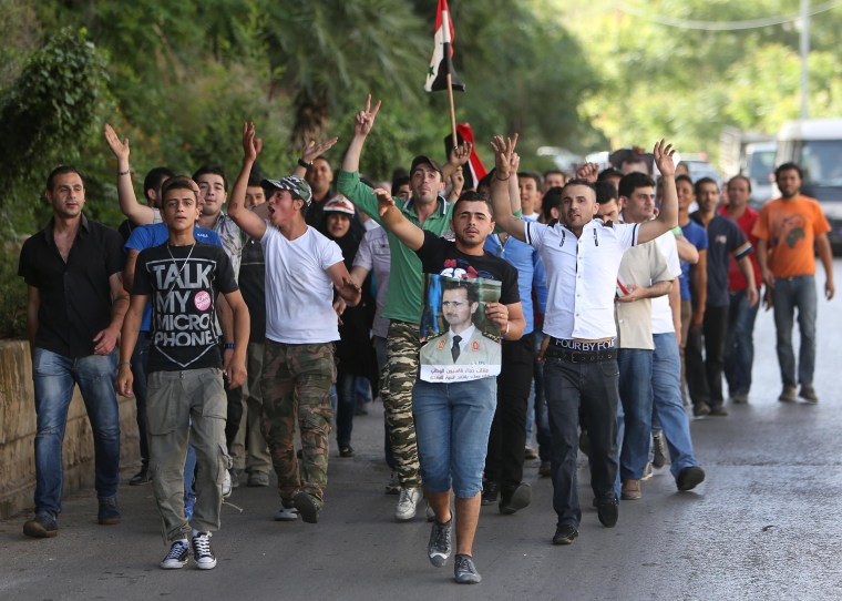 Image: Syrian citizens who live in Lebanon shout slogans and carry a portrait of Syrian President Bashar Assad