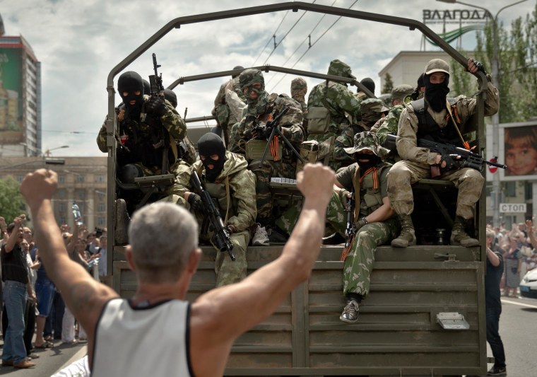 Image: A man cheers as pro-Russian gunmen drive away in a truck in Lenin square in Donetsk, Ukraine