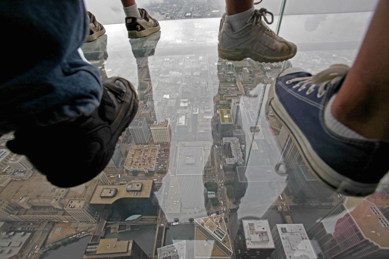 Visitors stand on "The Ledge," a glass balcony suspended 1,353 feet (412 meters) in the air from the Willis Tower's 103rd floor Skydeck.