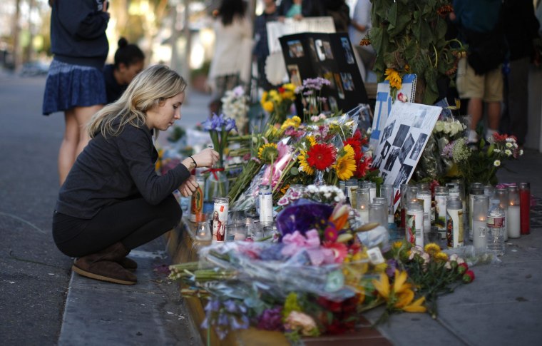 Image: A woman lights a candle at memorial for UCSB shooting victim