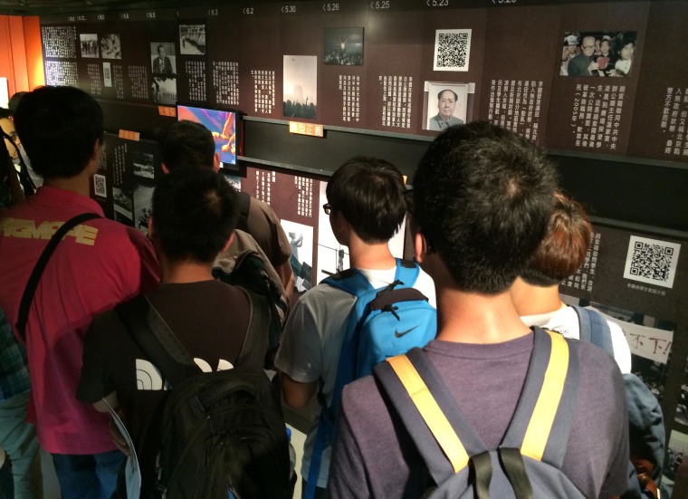 Young Chinese mainlanders crowd around a video at the June 4 museum in Hong Kong.