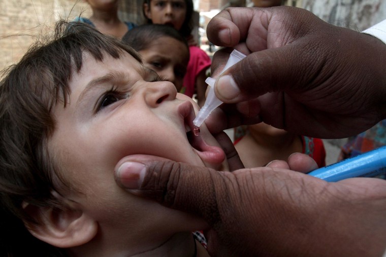 Image: A health worker gives a polio vaccine to a child in Lahore, Pakistan
