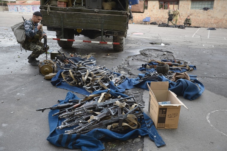 Image: Militants collect weapons and ammunition after they seized a National Guard base in Lugansk