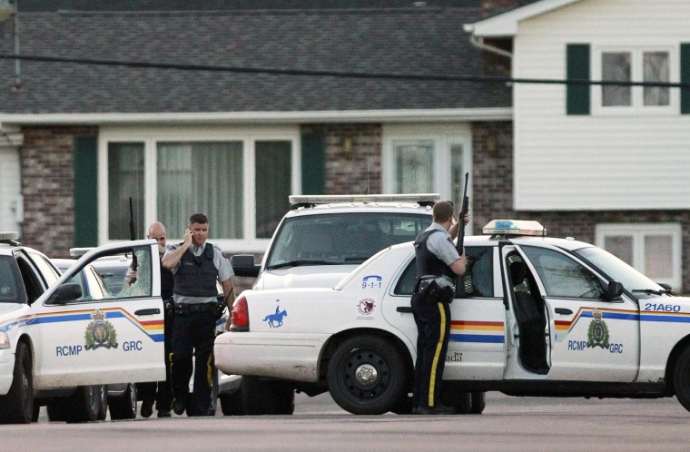 Image: Codiac RCMP officers take cover behind their vehicle in Moncton