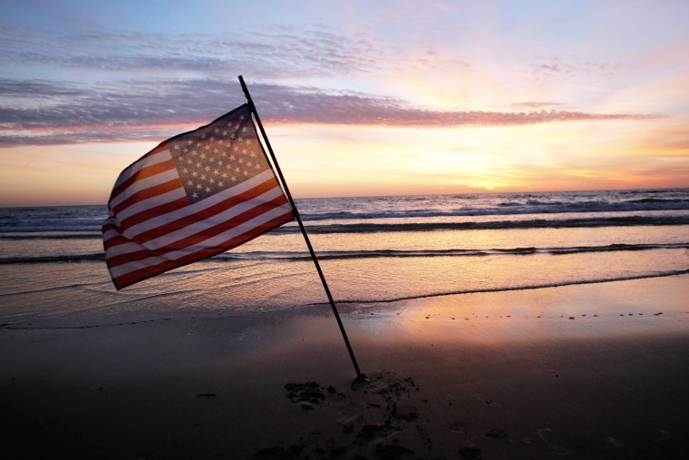 Image: An American flag is placed in the sand of Omaha Beach, western France