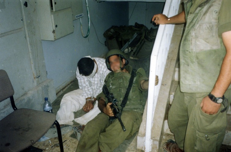 An Israeli soldier poses with a Palestinian detainee in an undated photo taken by a fellow soldier and made available by the campaign group Breaking the Silence.