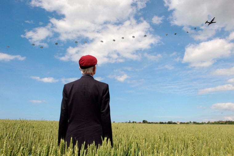 Image: British World War II veteran Frederick Glover poses for a photograph as soldiers parachute down during a D-Day commemoration paratroopers launch event in Ranville