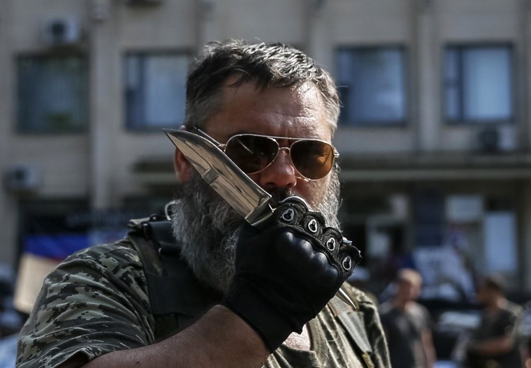 Image: A pro-Russian rebel holds a knife as he stands near a local government building in downtown Kramatorsk