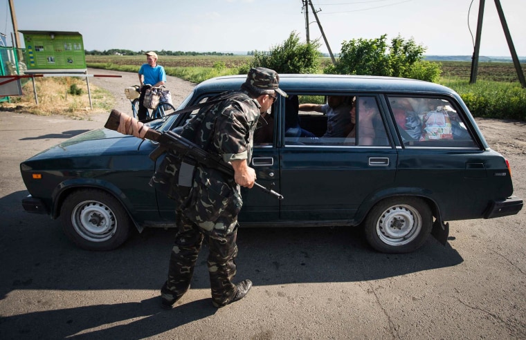 Image: An armed pro-Russian separatist speaks with passengers in a car leaving Ukraine at a border post abandoned by Ukrainian border guards at Chervonopartyzansk along the Ukraine-Russia border