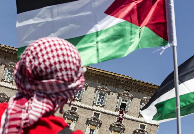Image: A man waves Palestinian flags as Pope Francis holds the Regina Coeli prayer in Saint Peter's Square