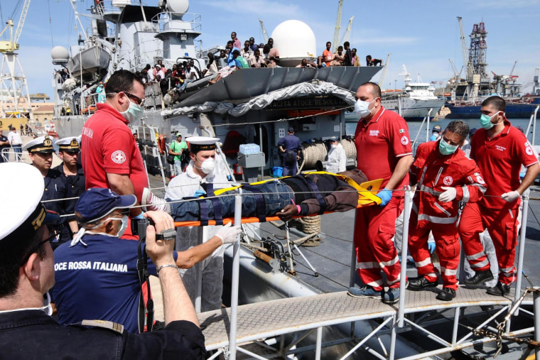 Image: A refugee is carried off an Italian Navy ship in the port of Palermo, Sicily