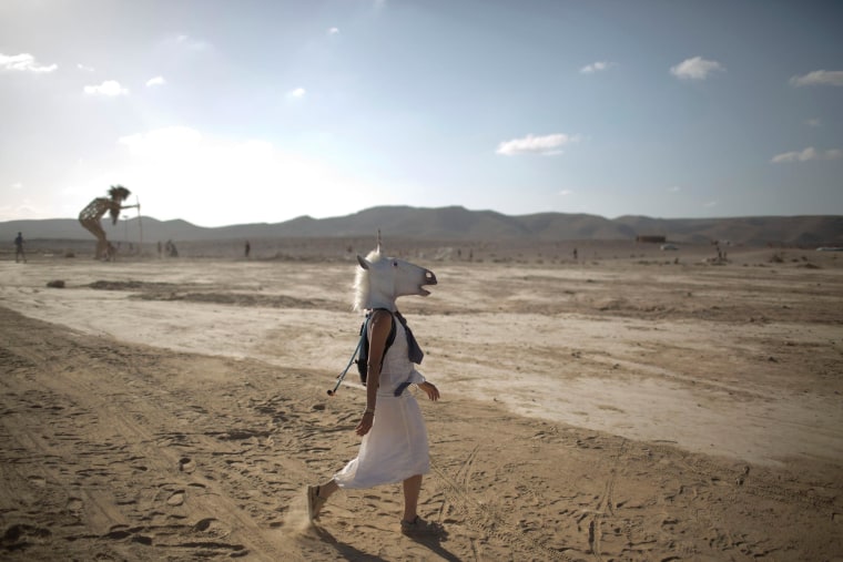 Image: An Israeli woman wears a unicorn mask as she walks in the playa during Israel’s first Midburn festival
