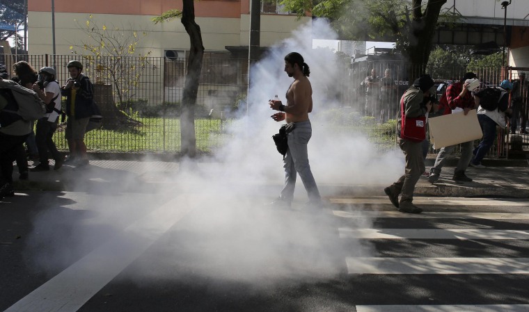 Image: Demostrator walks near to tear gas fired by mlitary police at demostrators during protest against 2014 World Cup in Sao Paulo