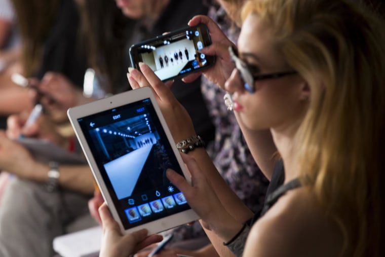 Image: A girl photographs the Kingston University show on an iPad during day 3 of Graduate Fashion Week 2014 at The Old Truman Brewery on June 2 in London, England.