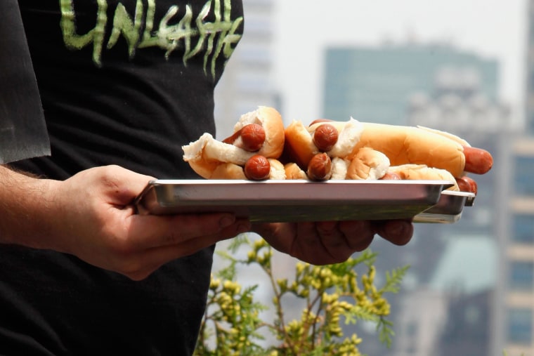 Image: A man carries a plate of hot dogs