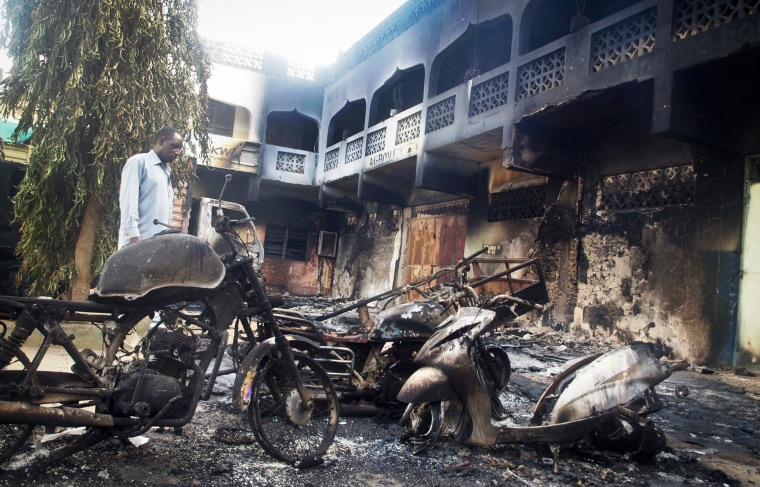 Image: The remains of destroyed vehicles and buildings in the town of Mpeketoni