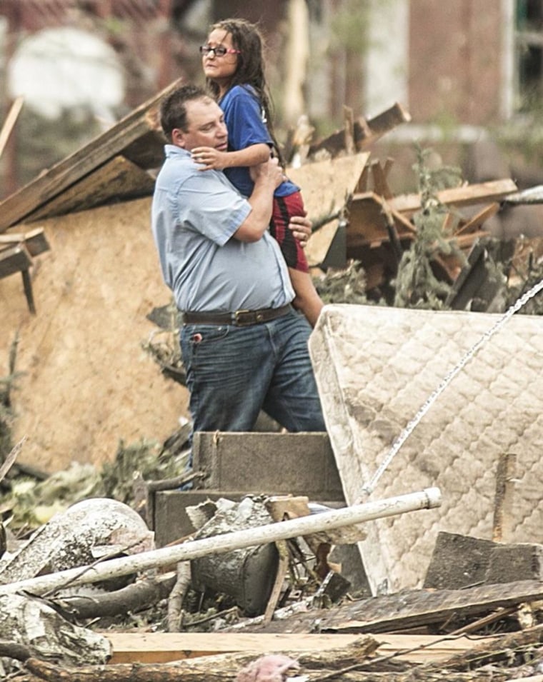 Image: A man holds a girl after she was pulled from the basement of her destroyed home in Pilger, Neb.