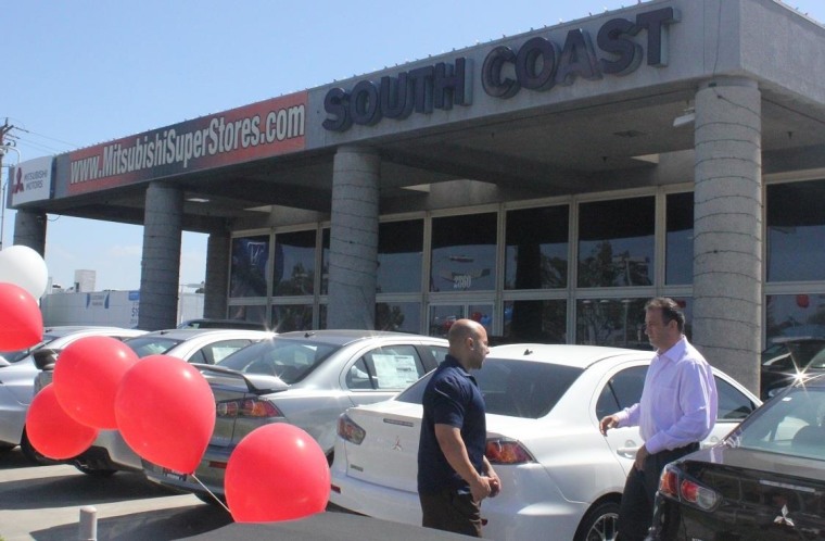 Abbas Ahmadi, right, talks with an employee at his South Coast Mitsubishi dealership in Costa Mesa, Calif.