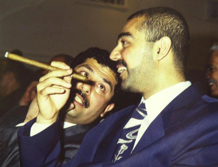 Saddam Hussein's eldest son Odai speaks with his younger brother Qusai