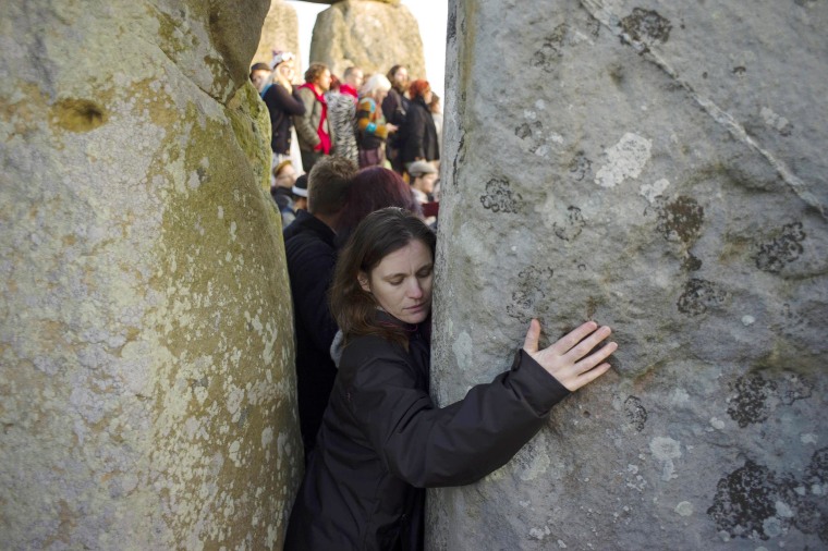 Image: A reveller hugs one of the stones as she celebrates the summer solstice on Salisbury Plain in southern England