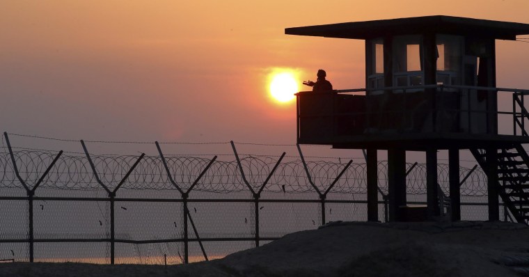 Image: A South Korean soldier guards with his gun at a guard post at sunrise on Baengnyeong Island, South Korea, near the West Sea border with North Korea on April 2
