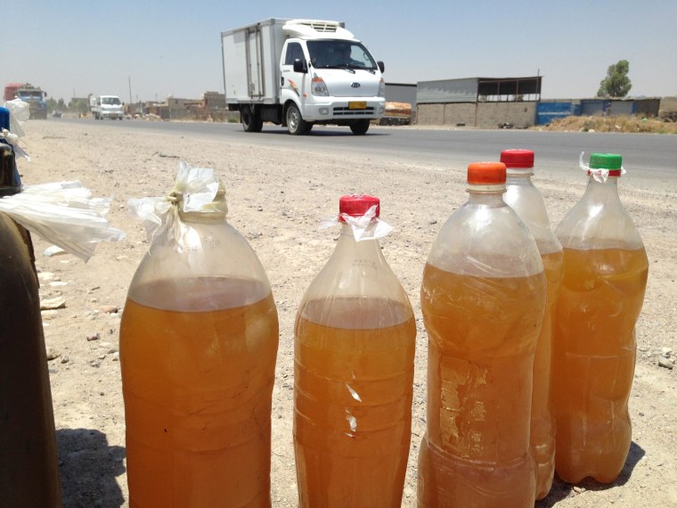 Image: Bottles of black-market fuel for sale on the side of a highway near Mosul, Iraq.