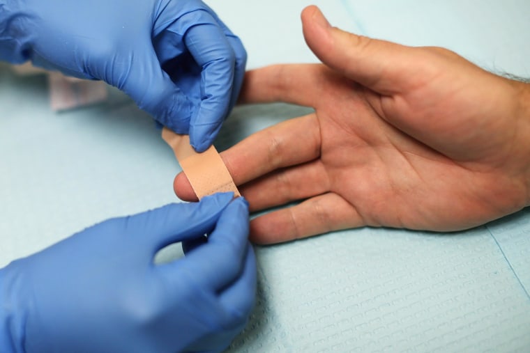 Image: A health educator puts a bandage on a man's finger after taking blood for an HIV test 