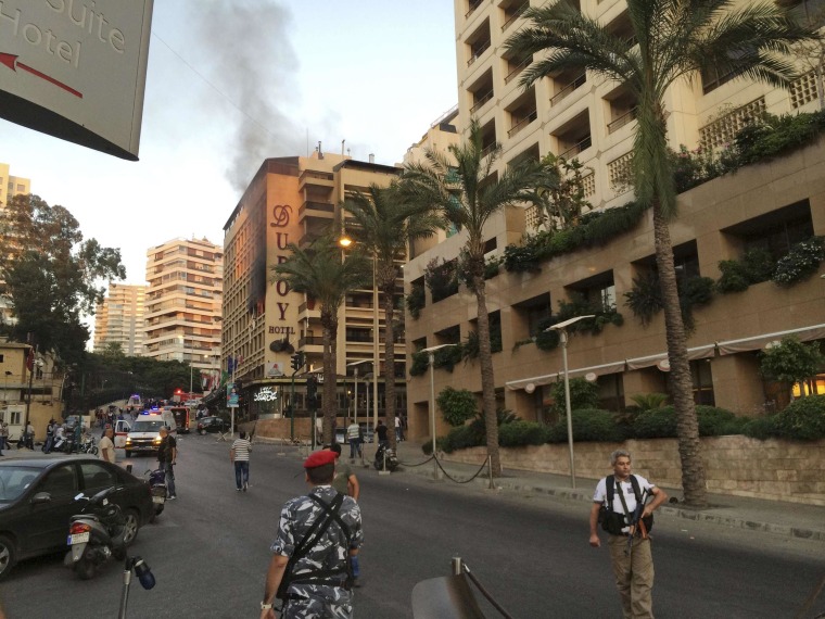 Image: Policemen and security officials secure the area as smoke rises from Duroy hotel in Raouche