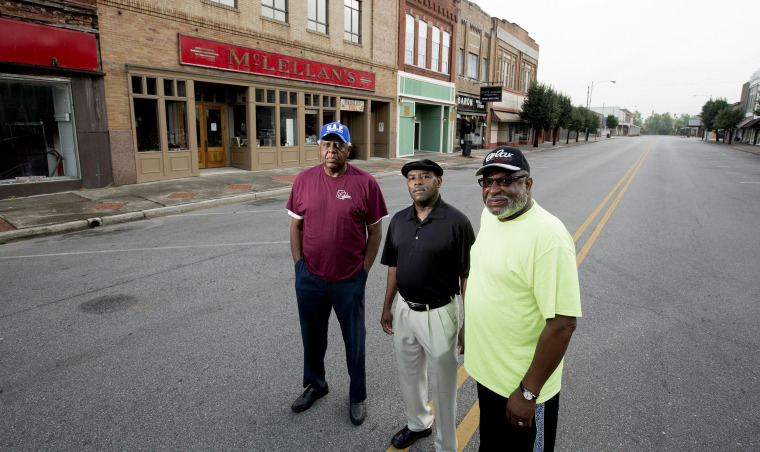 Image: Herman Williams , Desmond Wright  and Albert Shade stand outside of now the closed McLellan's department store almost fifty years after they staged a sit-in there to protest the whites-only lunch counter.
