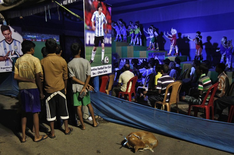 Image: Indian soccer fans watch 2014 World Cup soccer match between Argentina and Bosnia, on screen installed along roadside inside "Pandal" in Kolkata