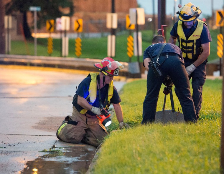 Image: Cedar Rapids Firefighters open a manhole cover as they try to locate a child reportedly swept into a sewer by storm water near the intersection of E Avenue and Oakland Road NE in Cedar Rapids