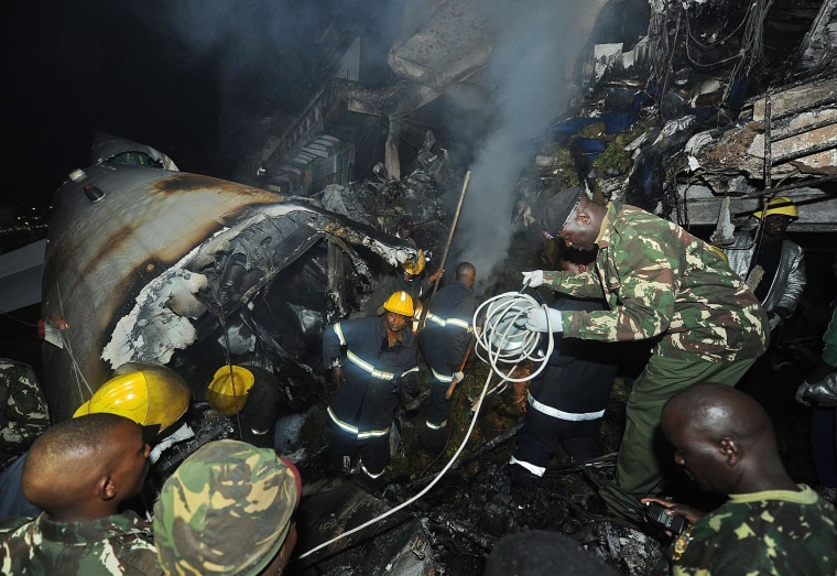 Image: Policemen and firefighters search in the wreckage of a cargo plane