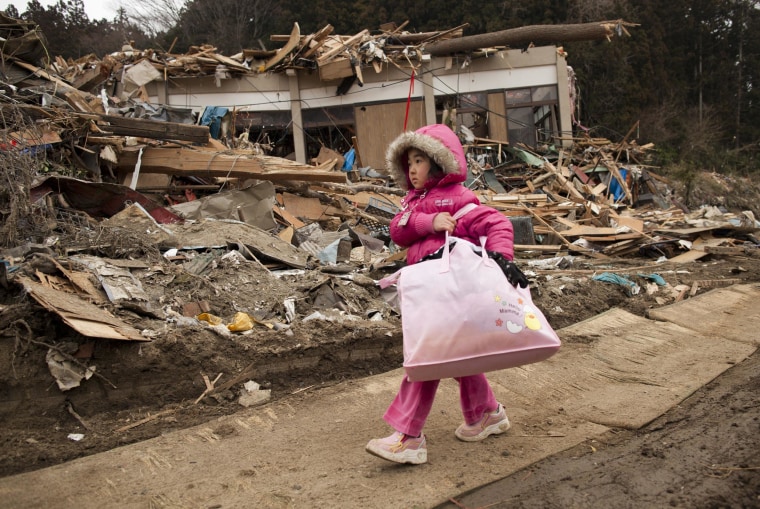 Image: Neena Sasaki, 5, carries some of the family belongings from her home that was destroyed after the devastating earthquake and tsunami on March 15, 2011 in Rikuzentakata, Miyagi province, Japan.