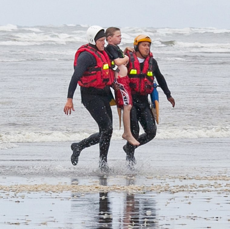 Image: Surf rescue swimmers Julez Orr and Eddie Mendez carry an 11-year-old boy to the shore at Long Beach, Wash.