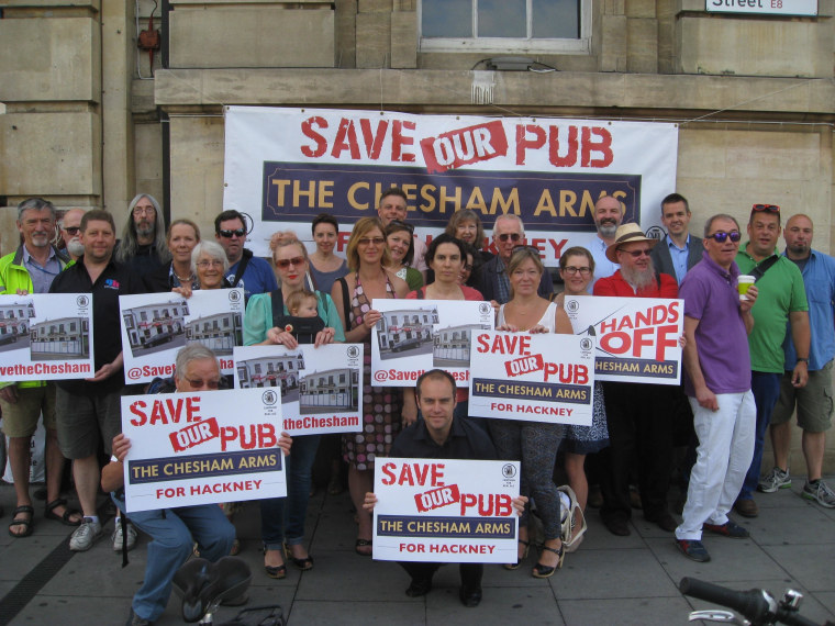 Image: Members of Save The Chesham, a neighborhood group in London fighting to have their local pub re-opened, show off their signs of protest.